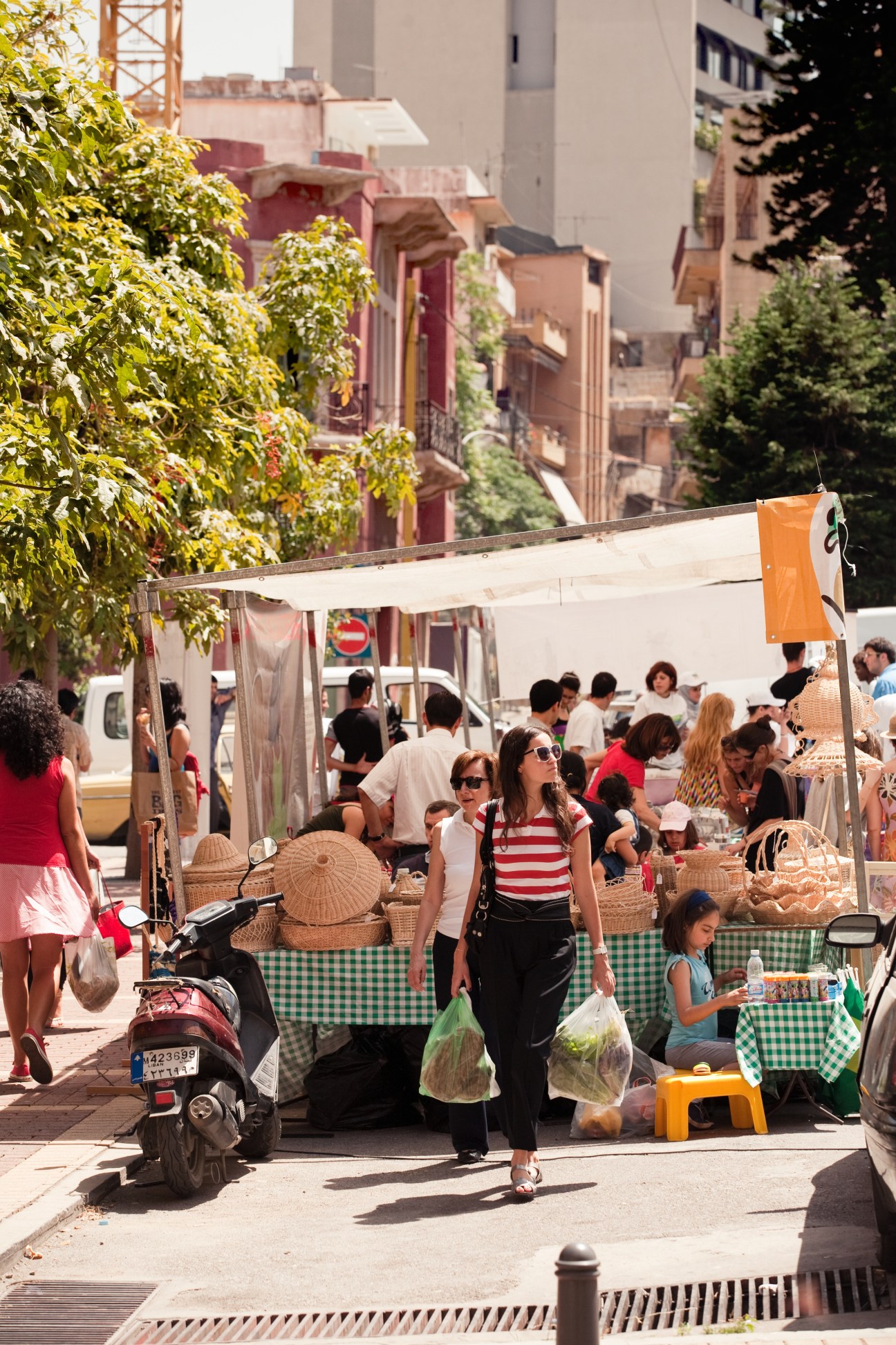 Shoppers browse vendors at Souk El Tayeb, Beirut's first farmers' market, under white awnings on a sunny street.
