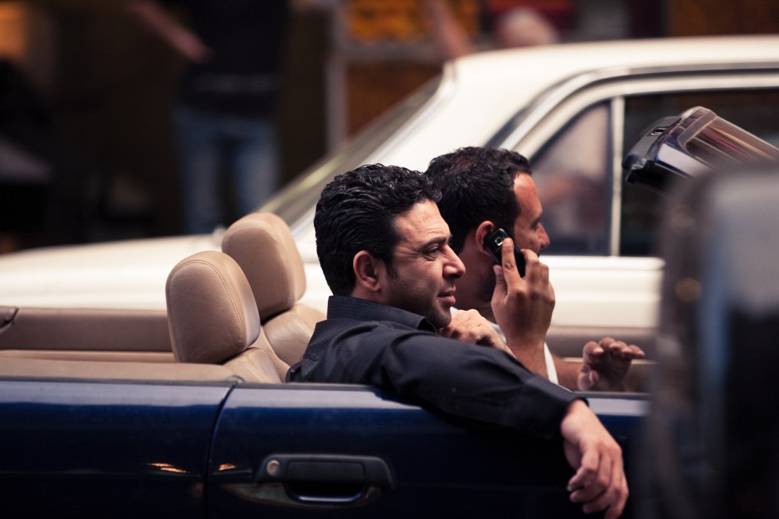 Two men in a convertible car with the top down on a Beirut street.