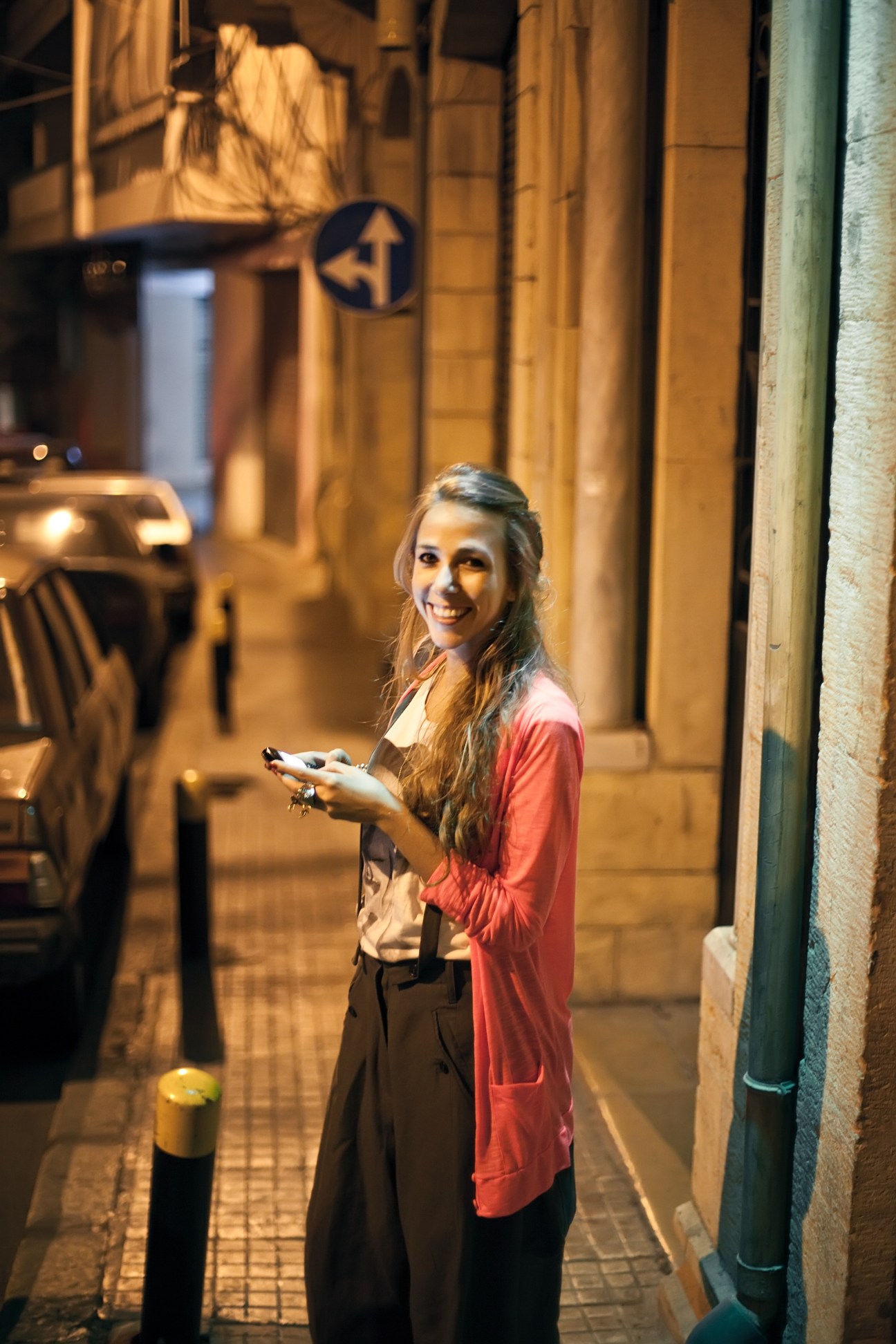 Fashion assistant Tala Hjiar sends a text outside Kayan bar on Rue de Liban in Beirut at night.