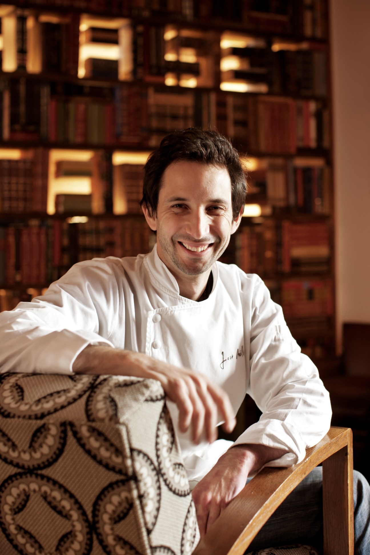 Chef José Avillez smiling at Belcanto restaurant in Lisbon, with illuminated signage visible behind him.