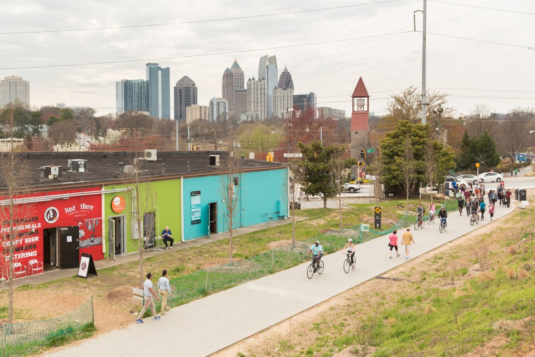 The Atlanta BeltLine pedestrian and cycle path with colorful food vendors, cyclists and pedestrians, with downtown Atlanta skyline in the background.