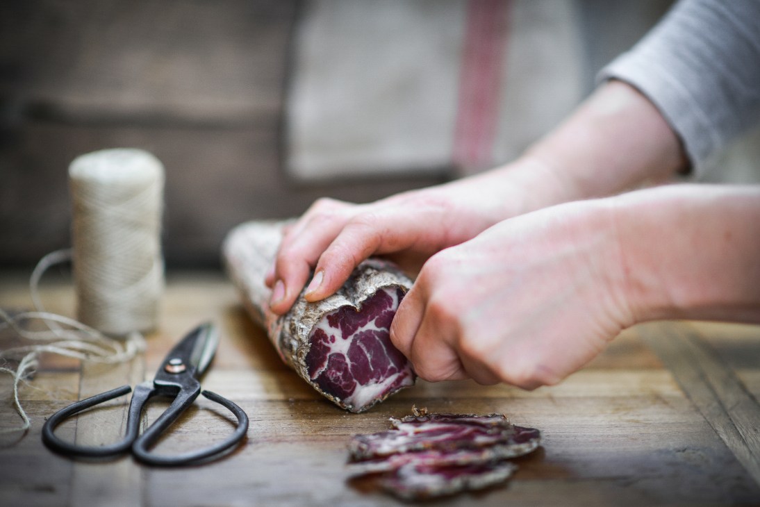Hands slicing cured meat at Bundarra Farm, Barham