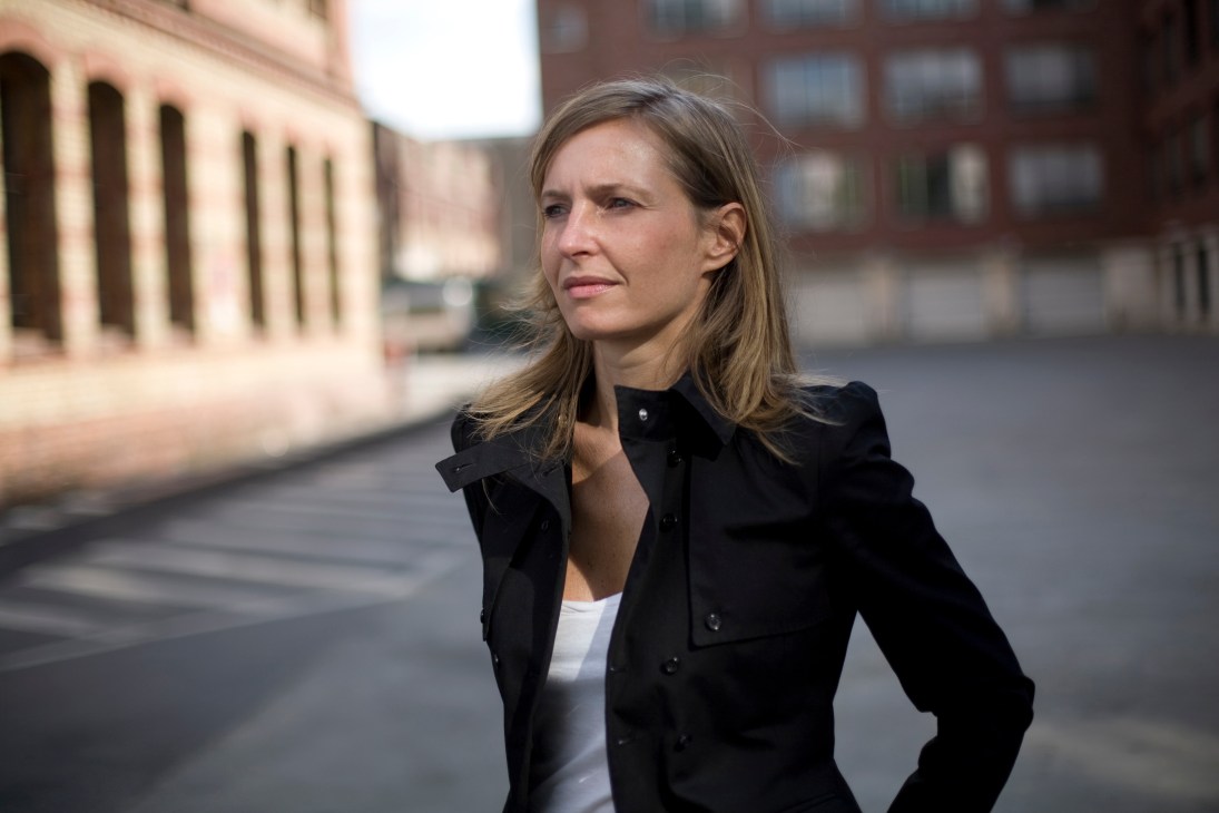 Tanja Mühlhans stands in a Berlin street wearing a black blazer, with historic buildings behind her.