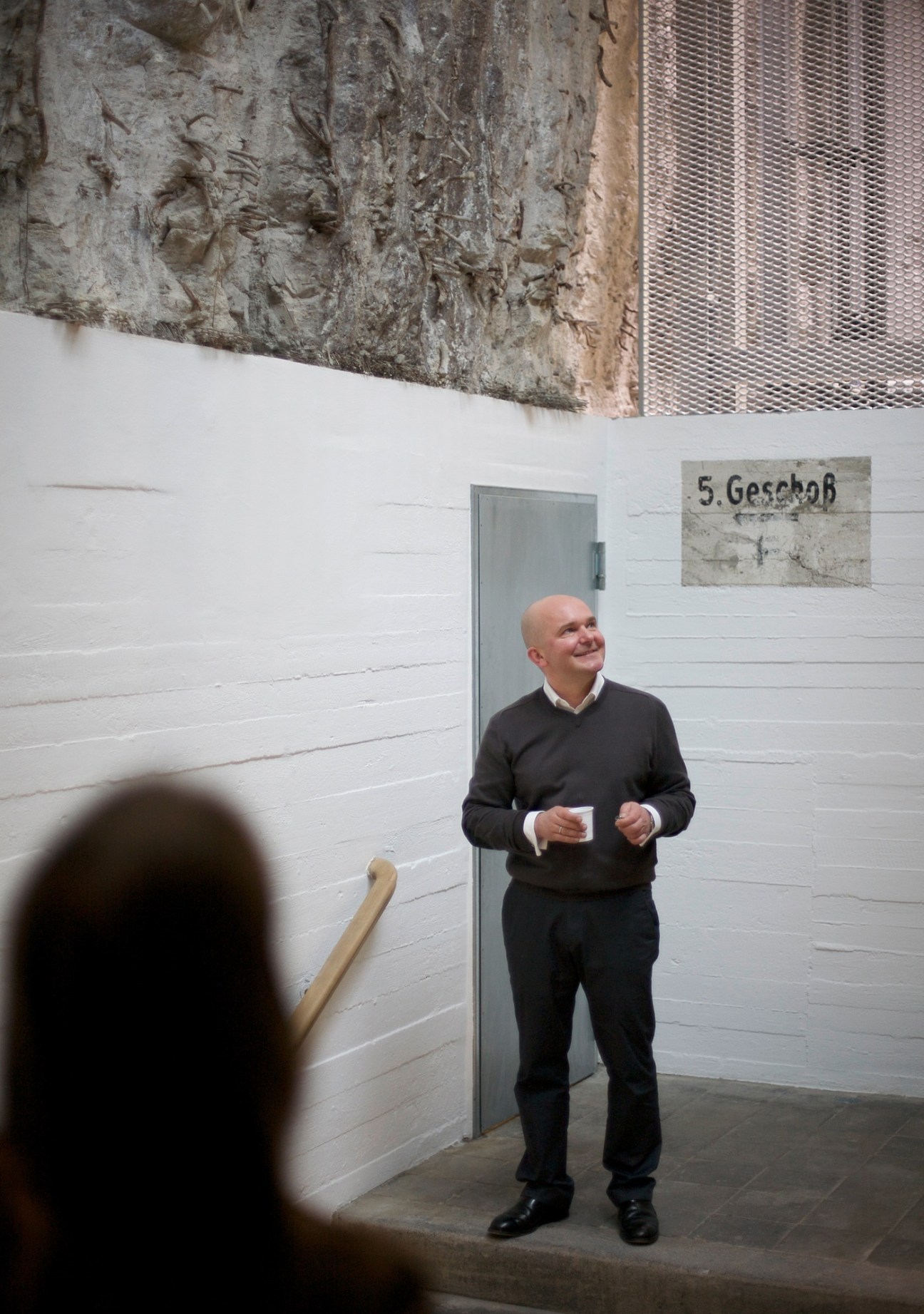 Christian Boros stands inside his gallery space in a former Nazi bunker with white walls and concrete ceiling.