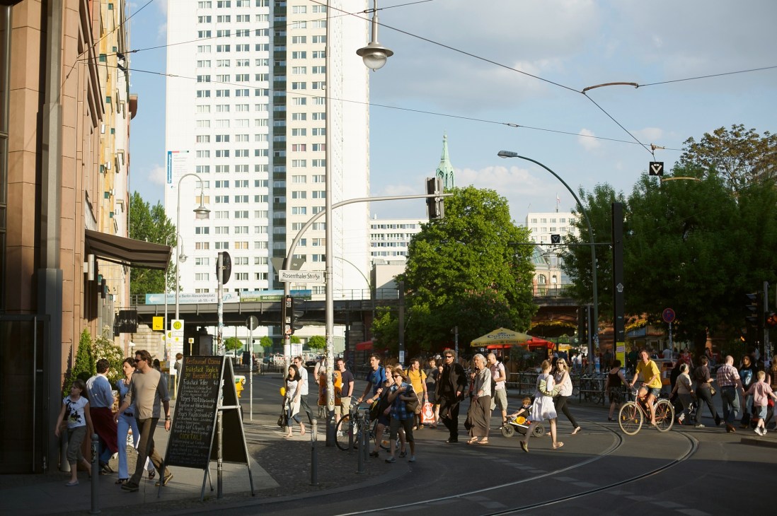 Bustling street scene at Hackescher market in Berlin Mitte with pedestrians, cyclists, and historic architecture.