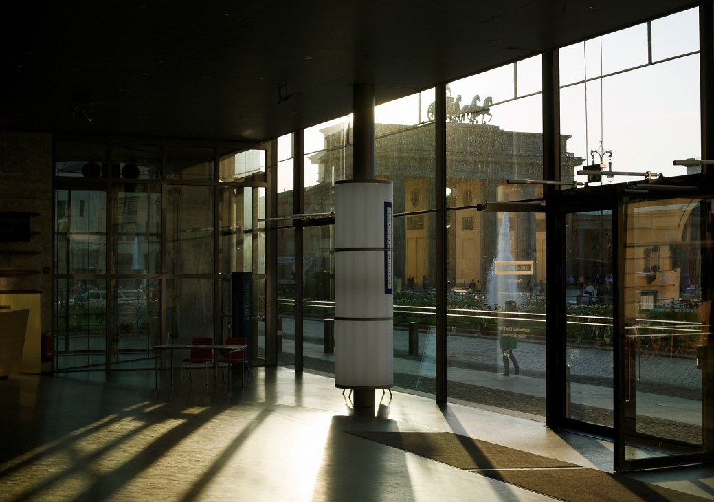 Interior of the Akademie der Künste in Mitte showing a modern glass and steel space with large windows overlooking the Brandenburg Gate.