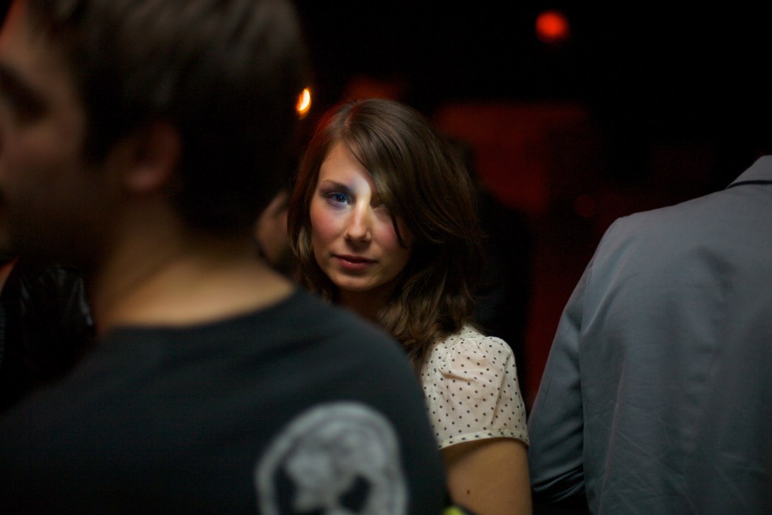 Woman in a polka-dot top at a nightclub surrounded by other clubbers in dark lighting.