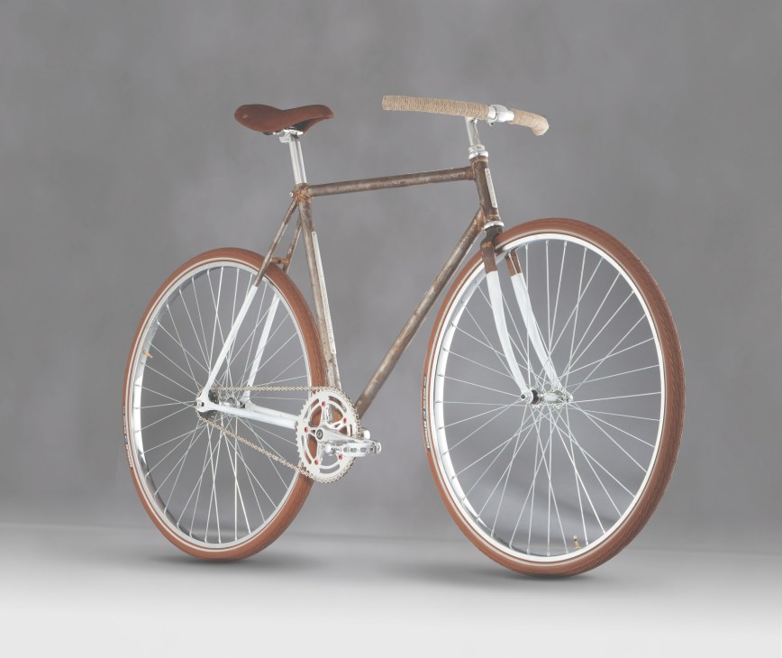 Hand-welded steel bicycle with brown leather saddle, wrapped handlebar, and rust-colored wheels by Italia Veloce.