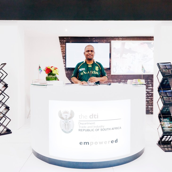Maboane Samuel, project manager of the South Africa Pavilion, stands at an exhibition booth with South African flag and branding.