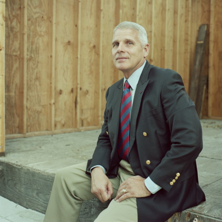 Lt (Ret) Gen Colby M Broadwater III, president of the American College of Building Arts, seated indoors against a wooden wall.