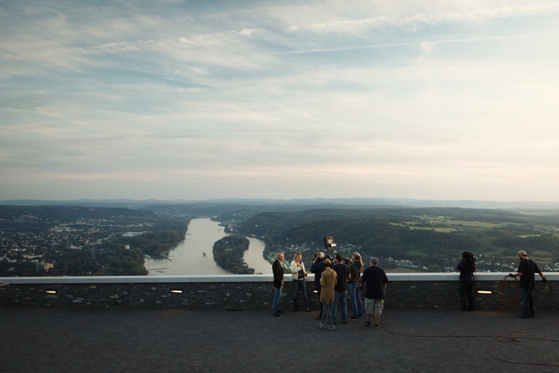Film crew gathered at an observation platform overlooking the Rhine River valley and Bonn below.