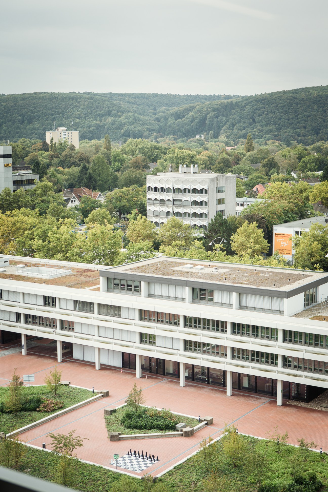 Modernist government building with courtyard overlooking forested hills in Bonn, Germany.