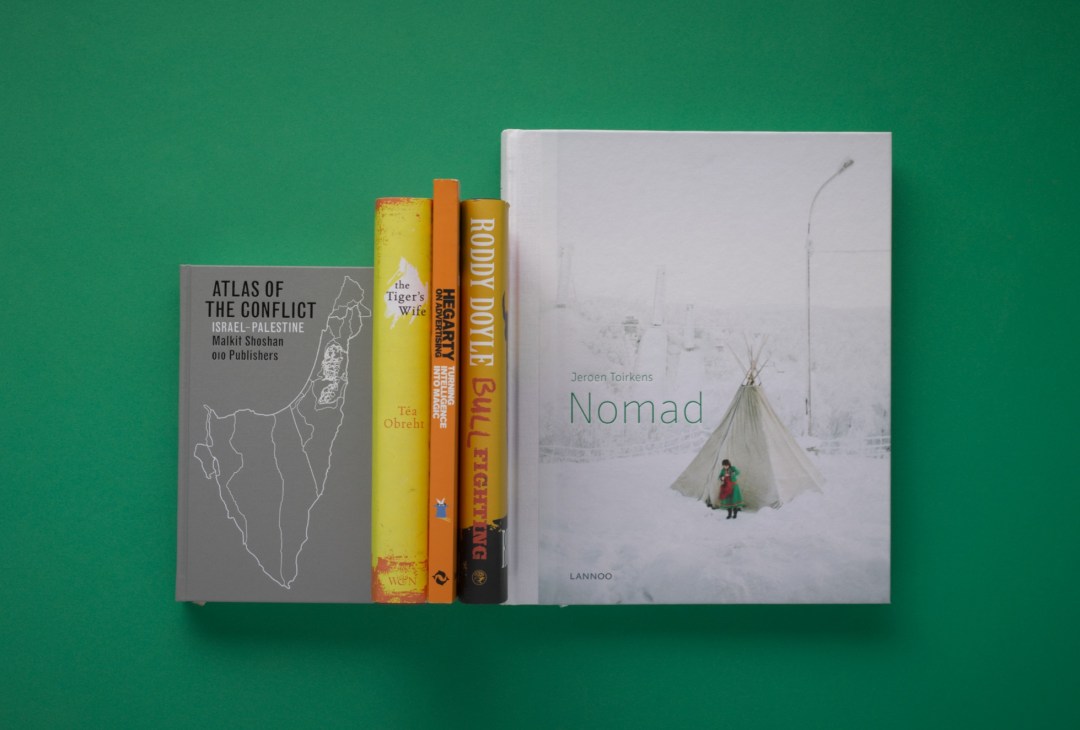 Five books displayed against a green background including Atlas of the Conflict, The Tiger's Wife, and Nomad by Jeroen Toirkens.