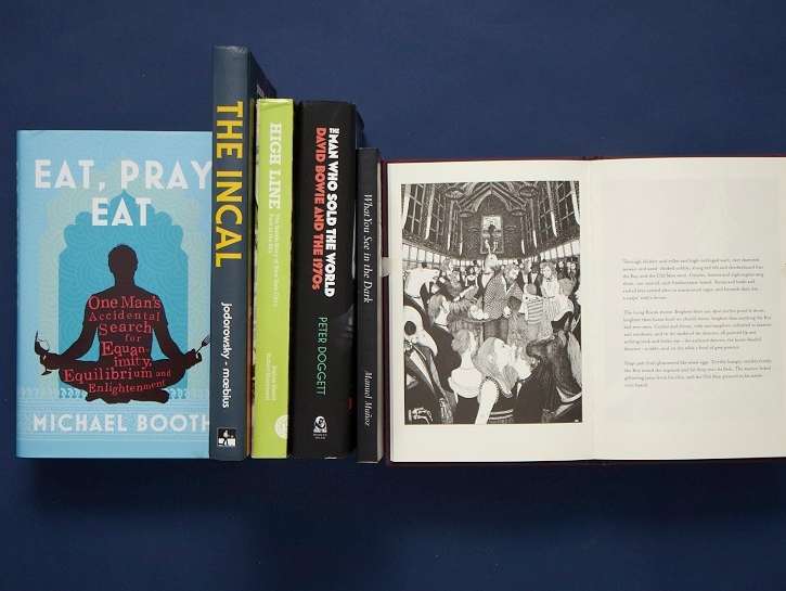 Collection of books displayed on dark blue background including Eat Pray Eat by Michael Booth and other titles.