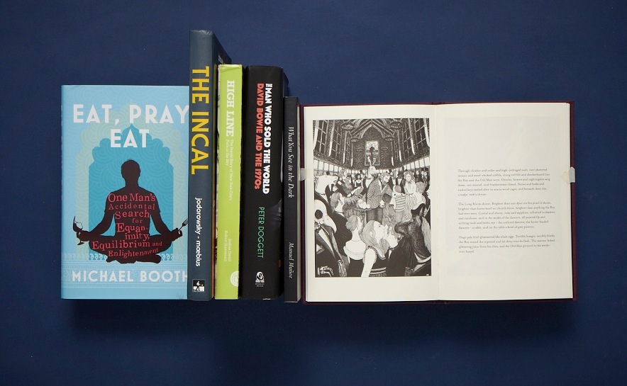Collection of books displayed on dark blue background including Eat Pray Eat by Michael Booth and other titles.