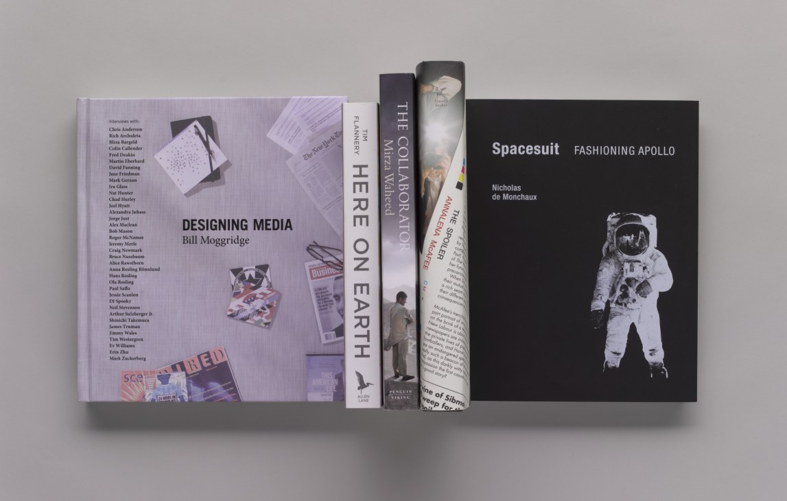 Collection of design and non-fiction books displayed in a row including Designing Media by Bill Moggridge and Spacesuit: Fashioning Apollo by Nicholas de Monchaux.