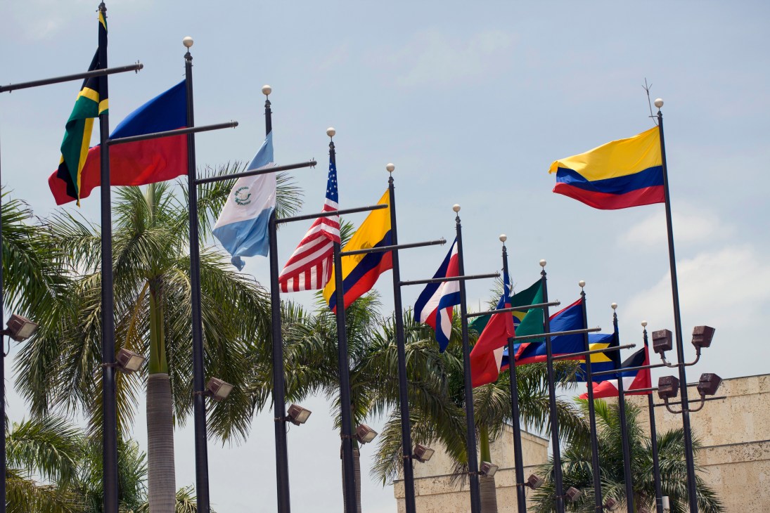 Multiple national flags displayed on poles including Colombia, USA, Brazil and other Americas nations at the Summit of the Americas.