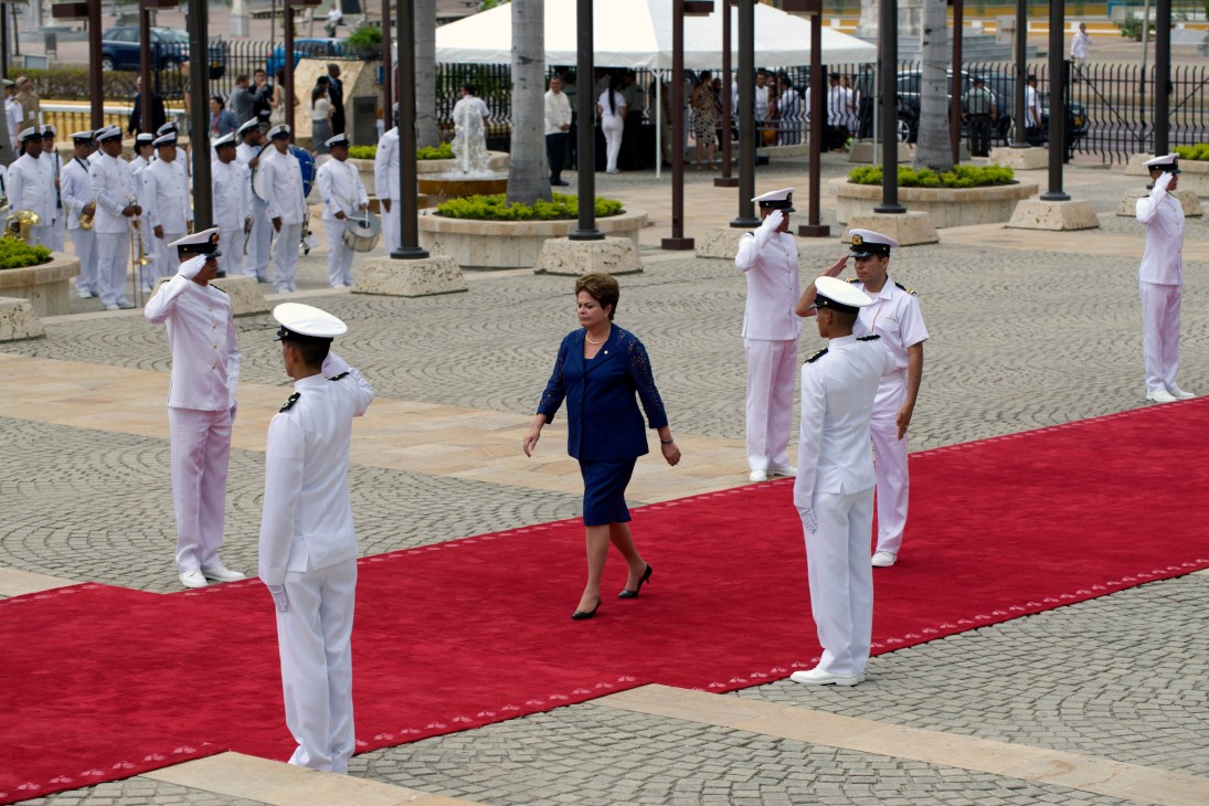 Brazil's president Dilma Rousseff walks on a red carpet flanked by naval officers in white uniforms at Cartagena summit.