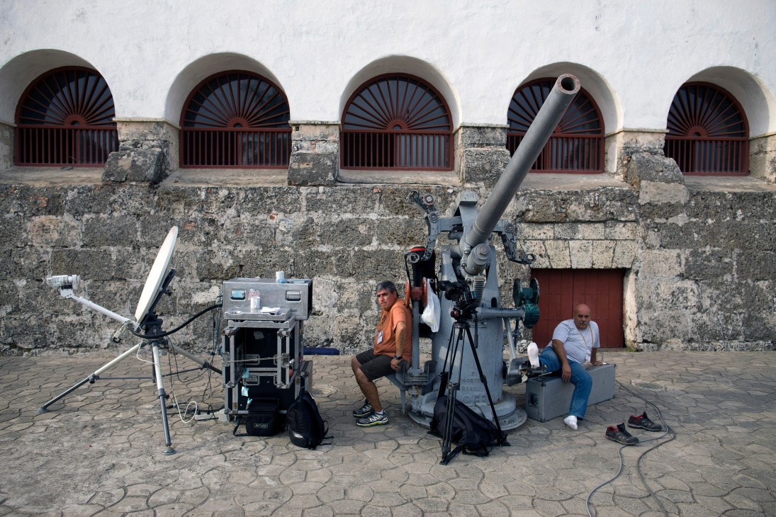 Media crews with broadcast equipment set up outside a colonial stone fortress in Cartagena.