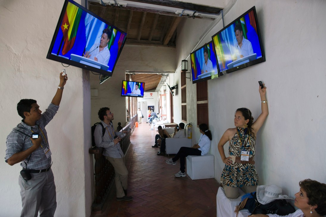 Media personnel watching President Santos's speech on multiple TV screens at the Summit of the Americas press centre.