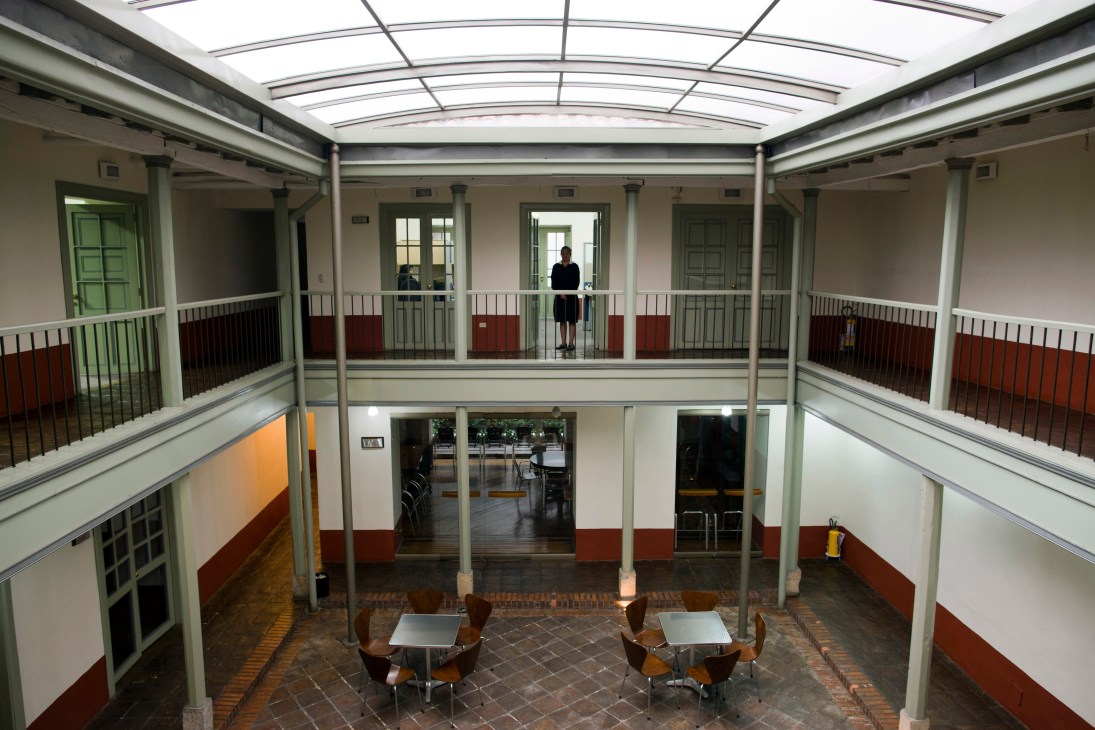 Interior courtyard of a restored colonial building with glass ceiling, white railings, and red-painted walls.