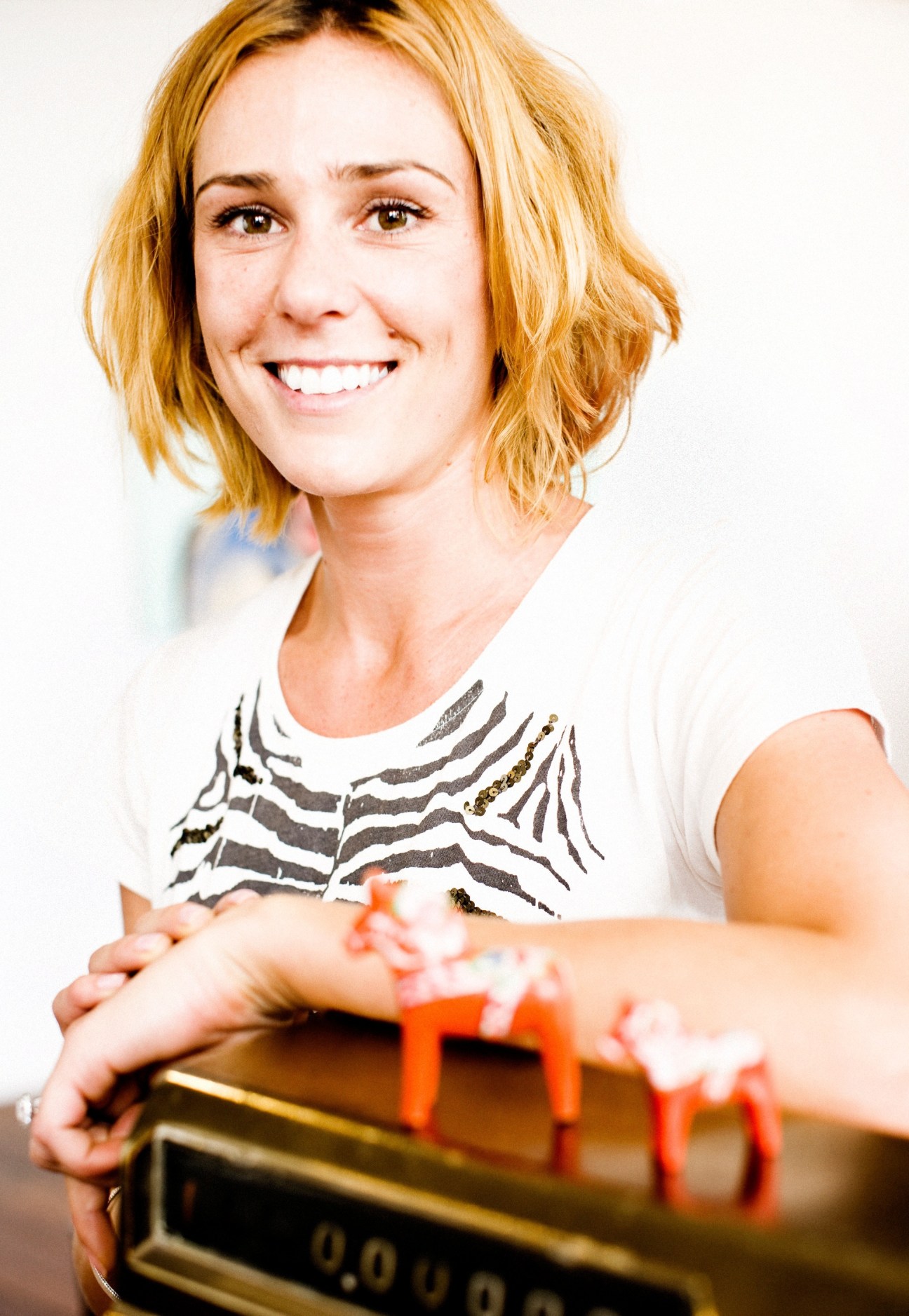 Woman with orange hair wearing a zebra-print top smiling while holding audio recording equipment