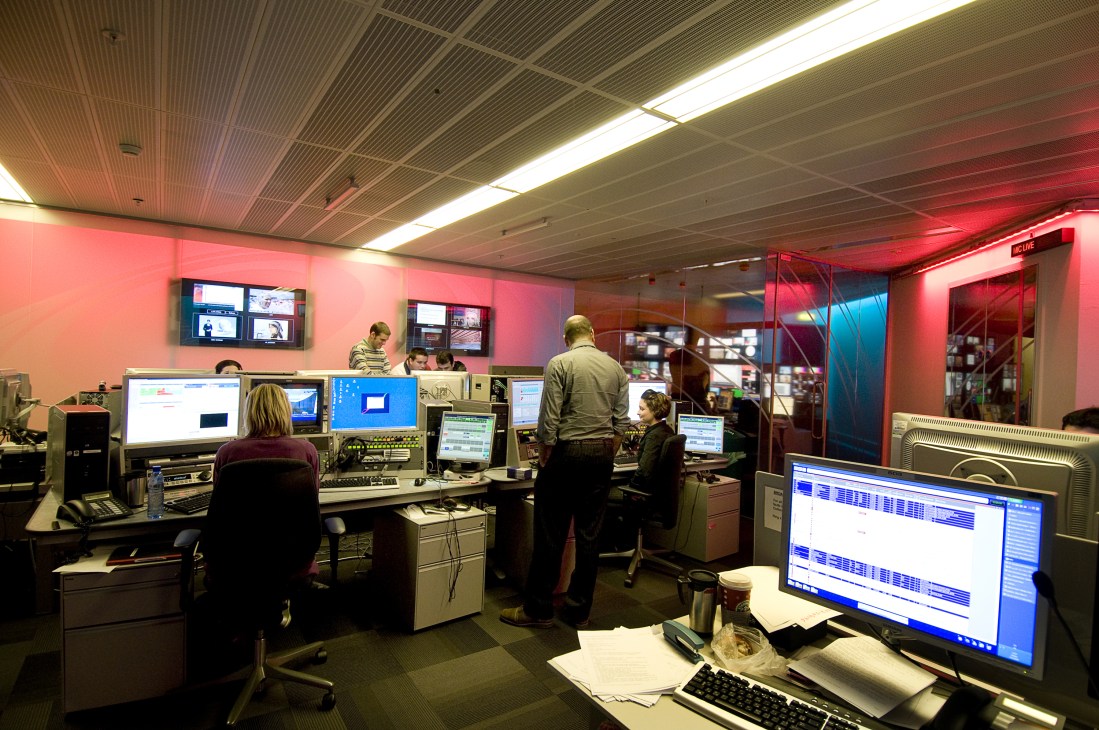 BBC Persian TV editing suite with staff working at computer workstations under pink and blue lighting.