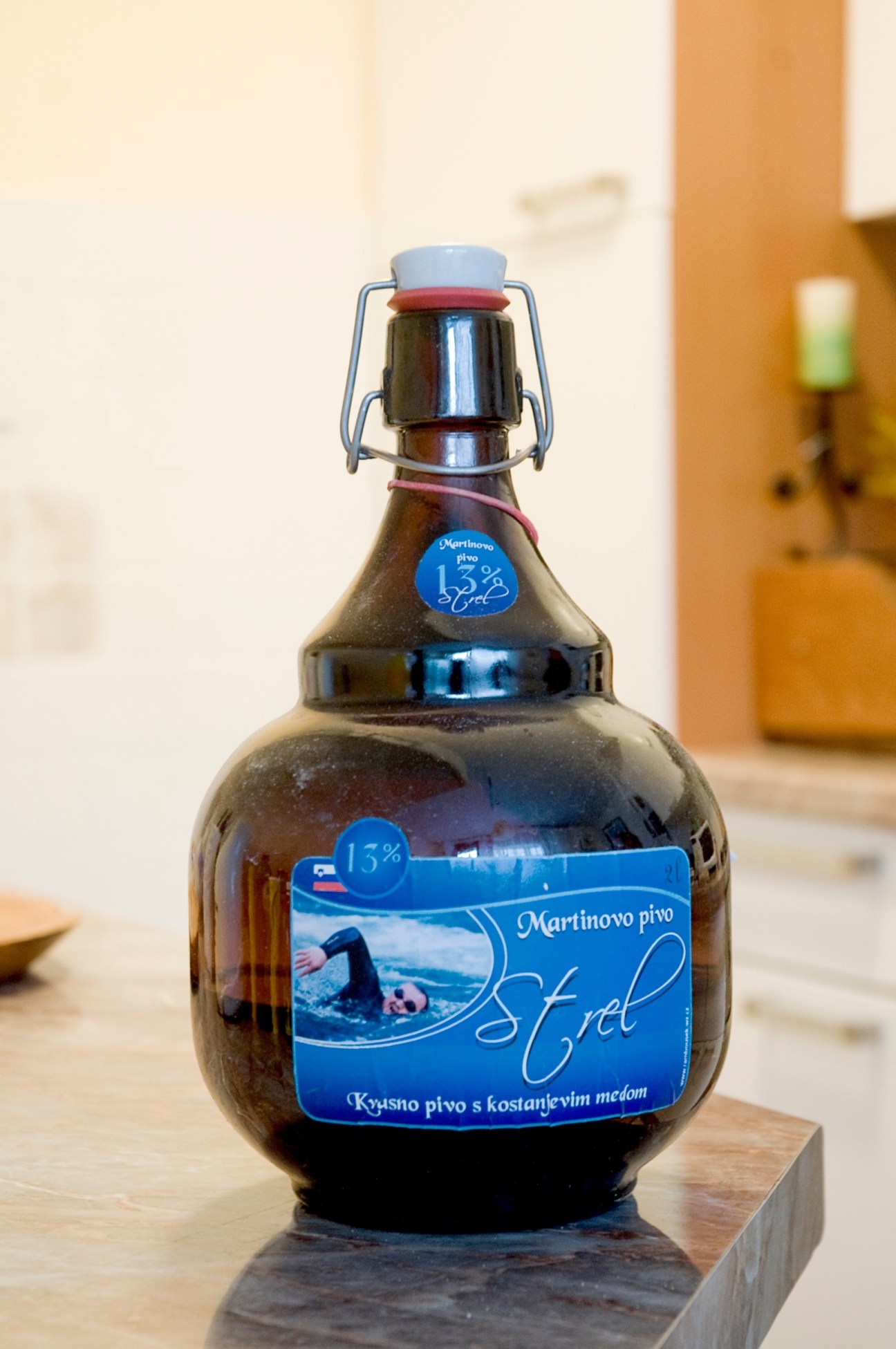 Bottle of Martinovo pivo beer with blue label featuring Martin Strel swimming, with swing-top closure.