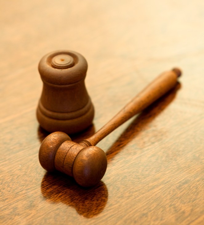 Wooden auctioneer's gavel and sound block on a wooden surface.