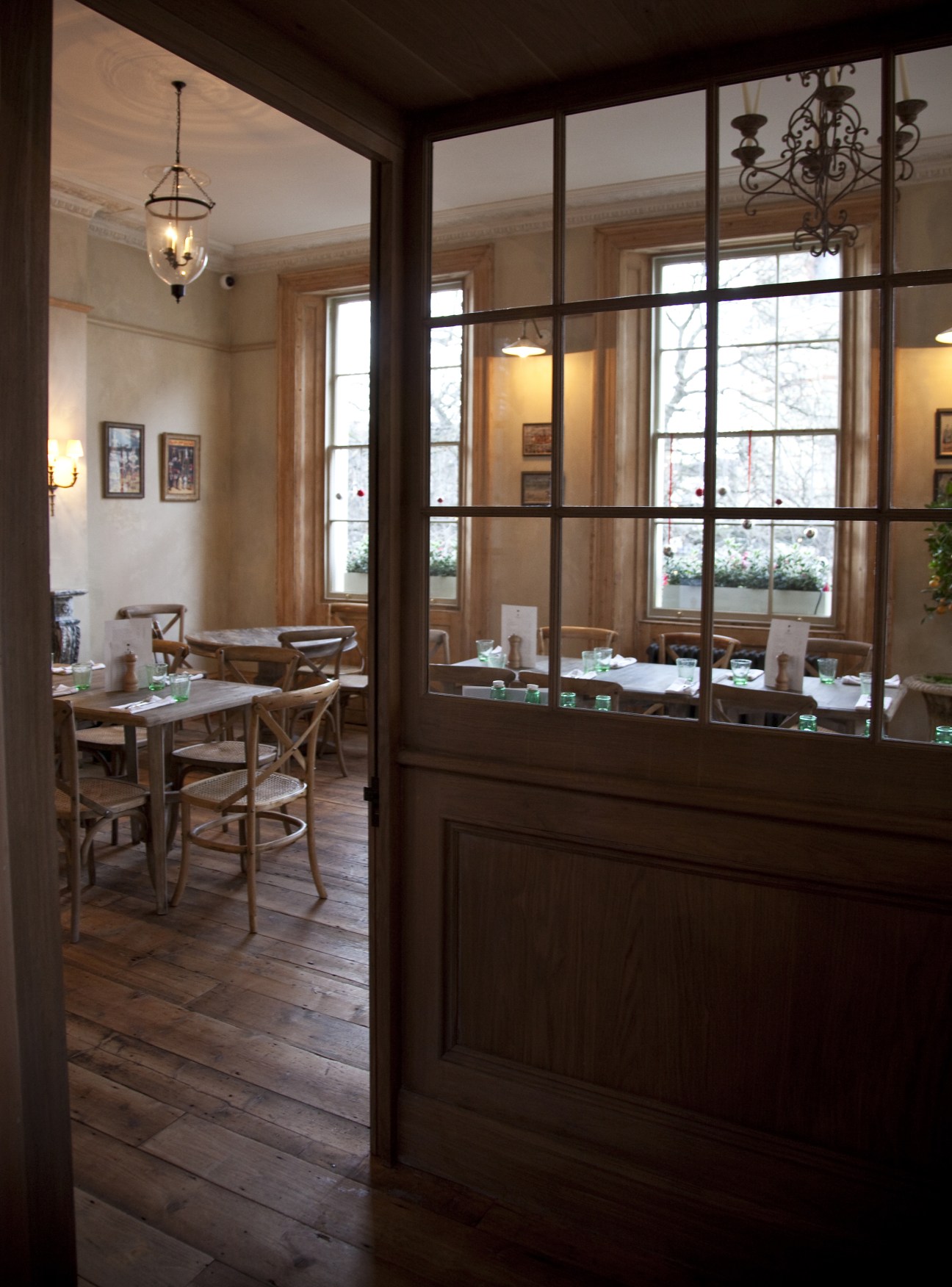 The Orange hotel dining room in London with wooden tables, chairs, and large windows overlooking the street.