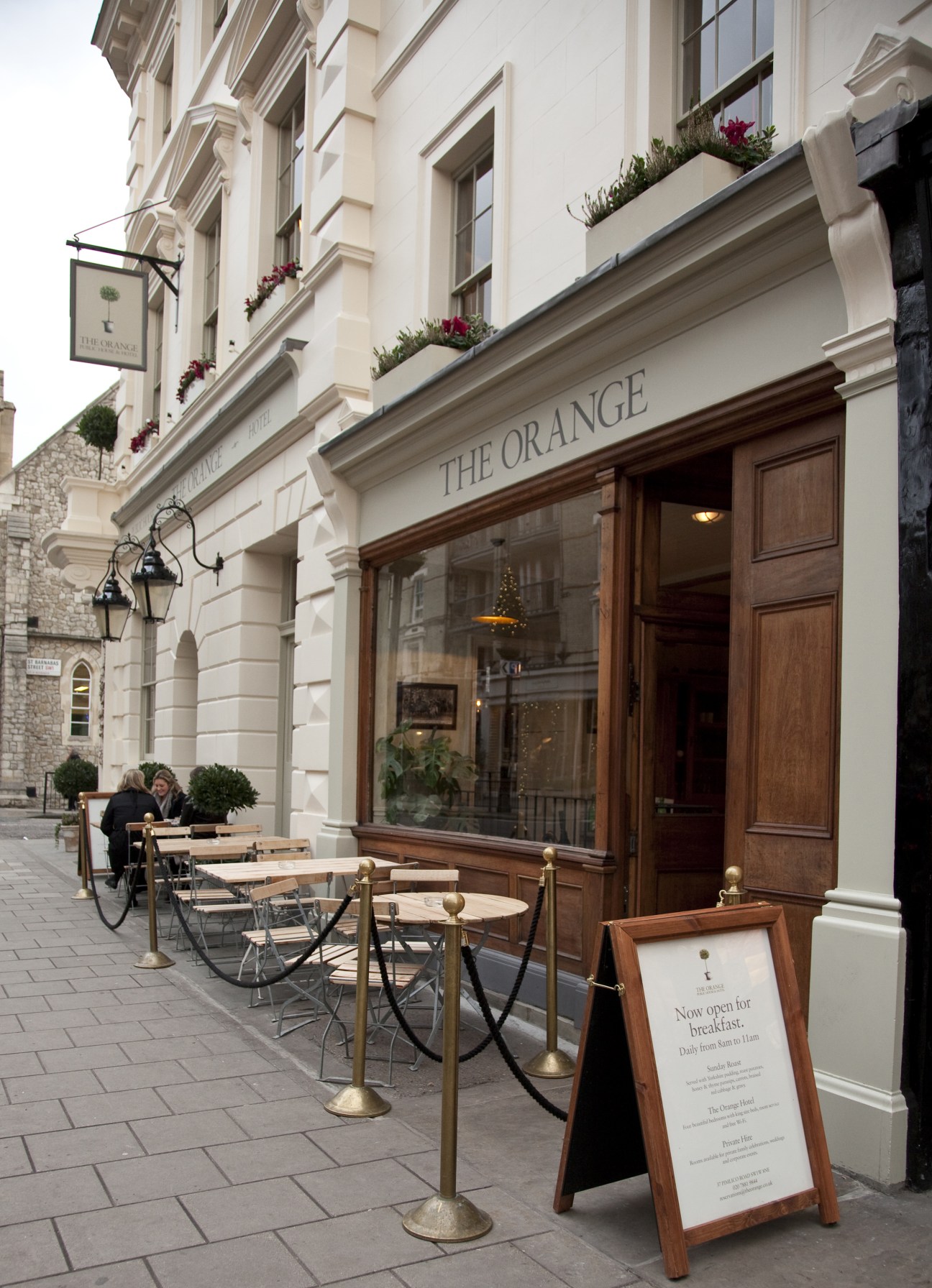 The Orange hotel entrance in London with outdoor café seating and classical architecture.