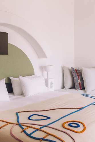 White hotel bed with colorful abstract pattern rug featuring blue and orange circular designs