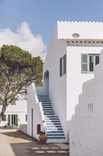 White Mediterranean-style building with blue staircase and traditional architecture in Menorca