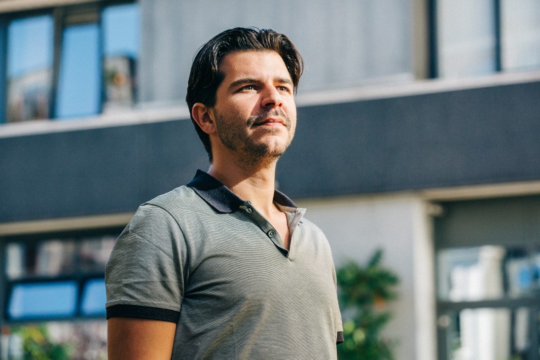 Rob Wijnberg, founder of De Correspondent, standing in front of a modern building in Amsterdam.