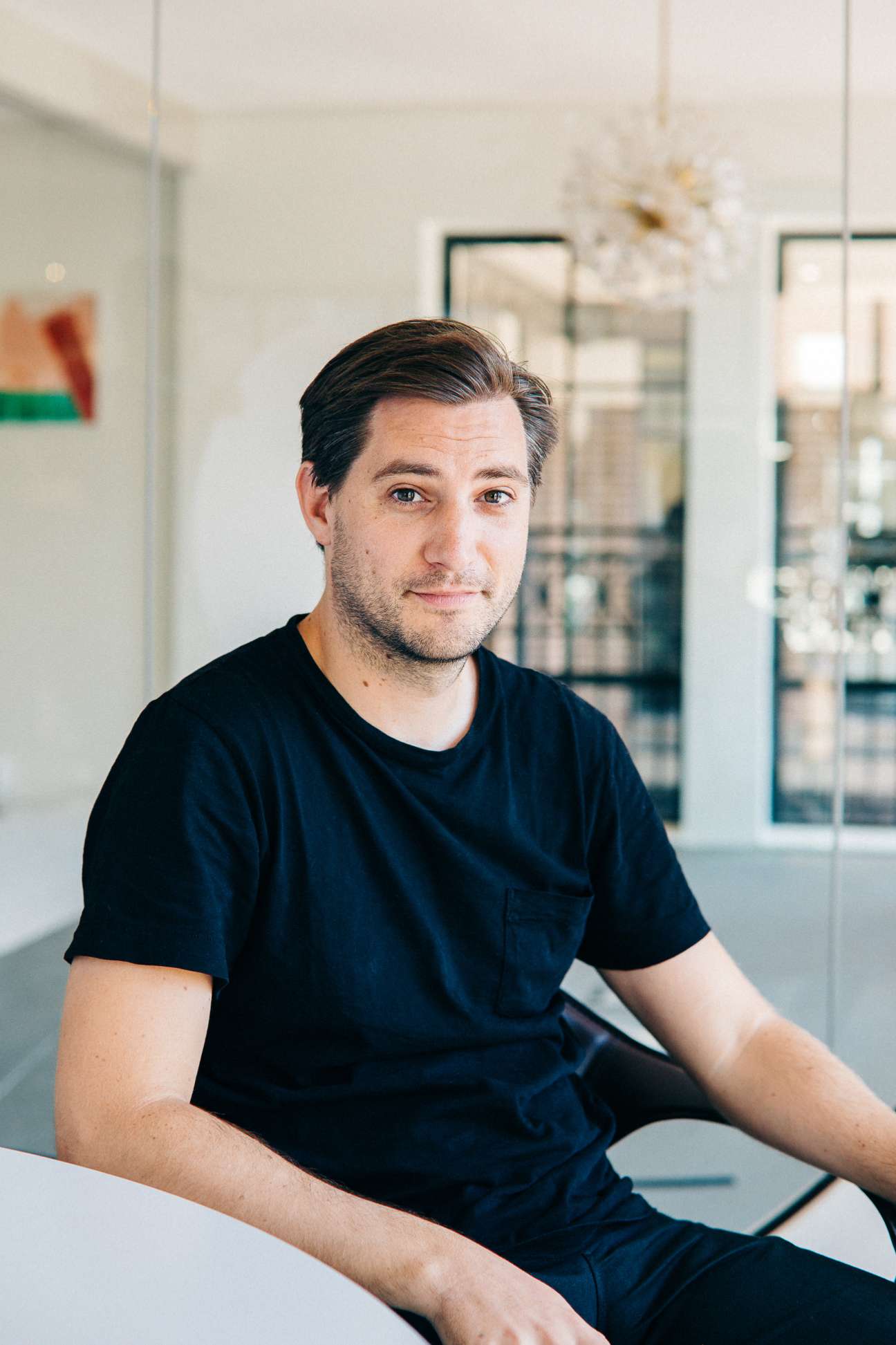 Nalden, WeTransfer co-founder, seated in a modern office with large windows and white walls.