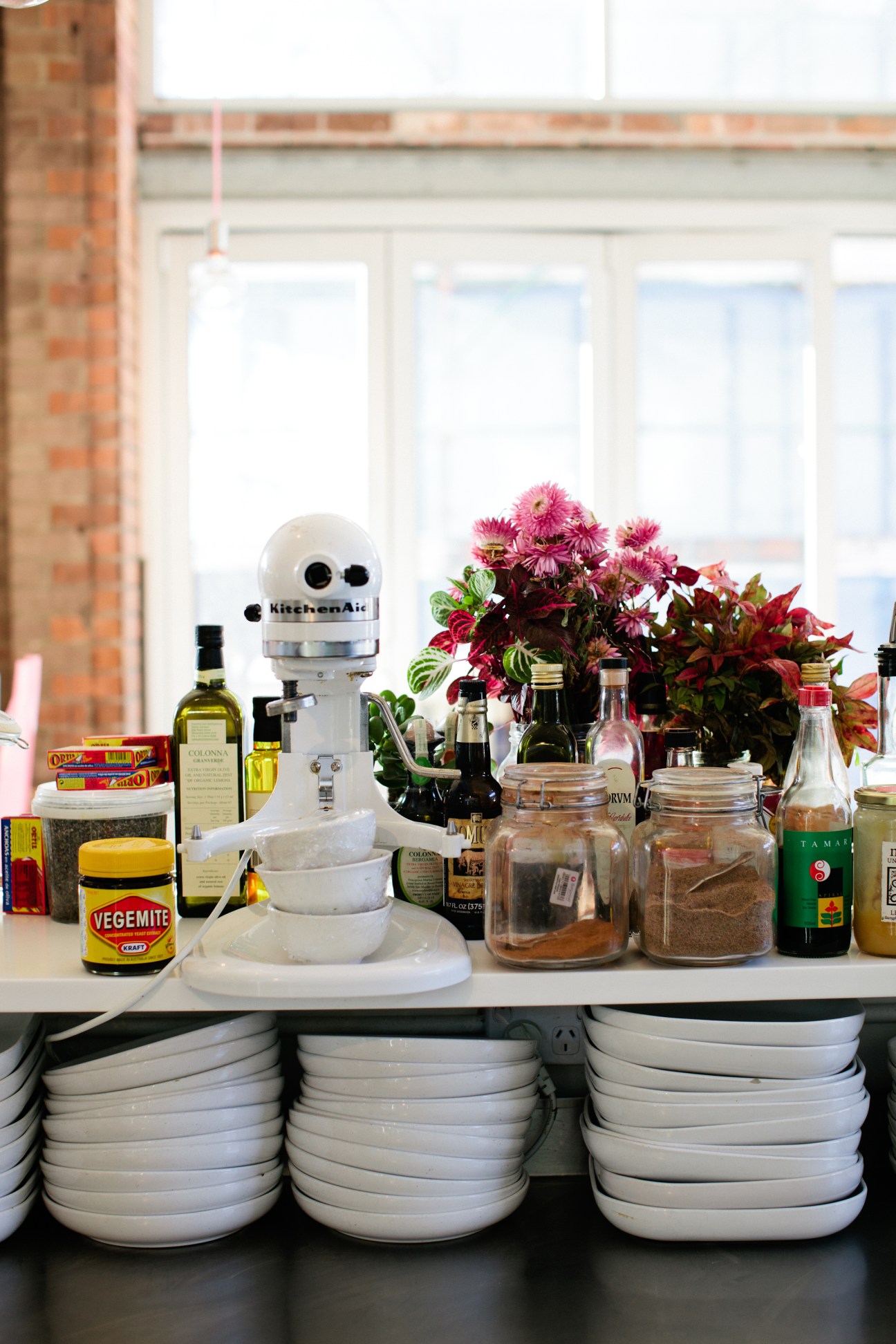 Kitchen counter display with KitchenAid mixer, bowls, cooking ingredients, flowers, and Vegemite jar.