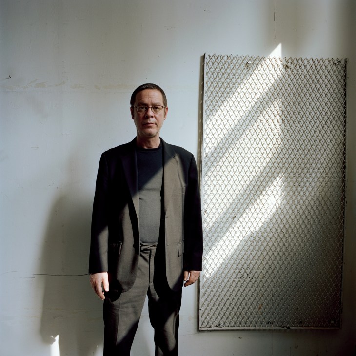 David Weinstein, managing director of AIR radio station, standing in a white studio space wearing glasses and a dark blazer over gray shirt.