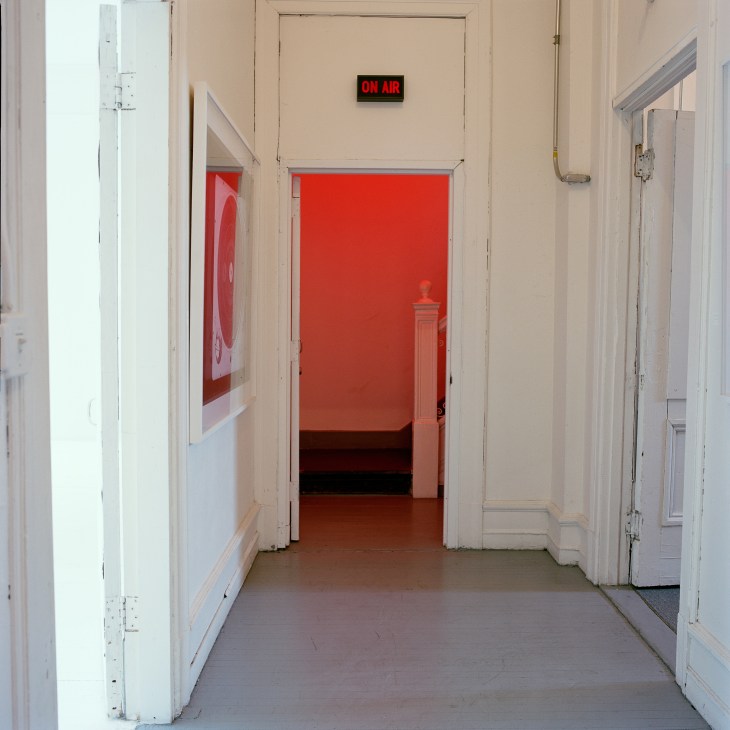 Hallway with red door and 'ON AIR' illuminated sign above doorway
