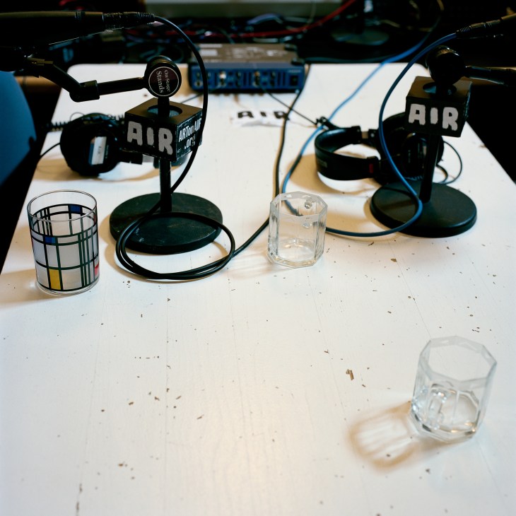 Multiple professional microphones with AIR branding on a studio desk with cables and water glasses.