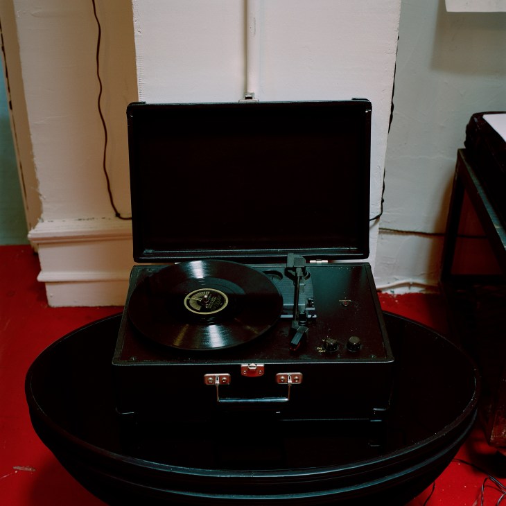Vintage portable record player with vinyl record on red surface in AIR studio.
