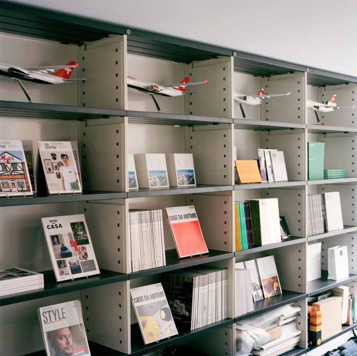 Green shelving displaying Winkreative project portfolios, magazines, model aircraft, and design materials.