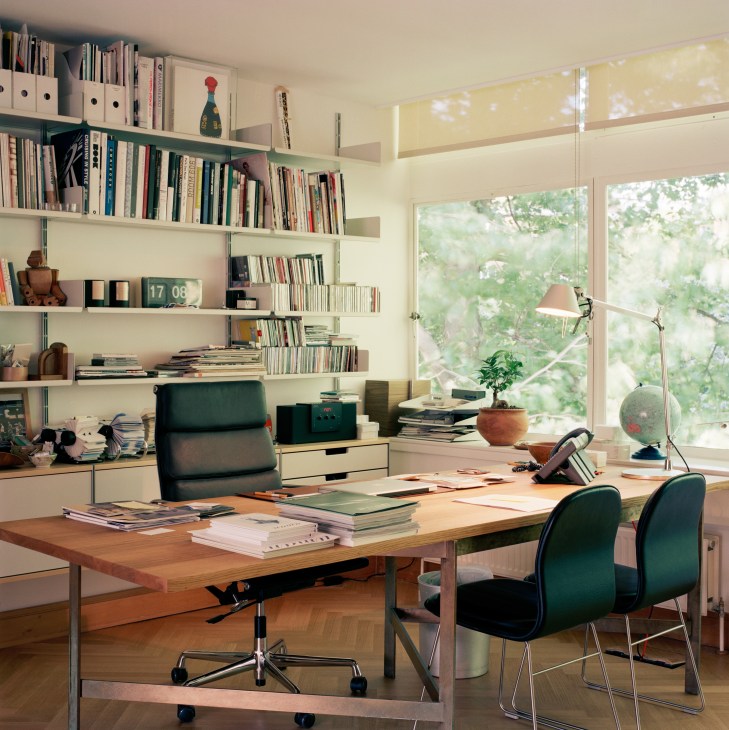 Editor-in-chief's office with Vitsoe shelving, Vitra Soft Pad chair, and BassamFellows oak and bronze desk overlooking gardens.