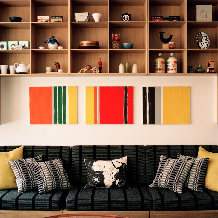 Custom wooden bookcase with curated decorative objects above a dark striped sofa with patterned pillows.