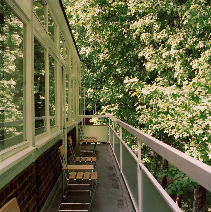 A narrow terrace with Grythyttan wooden chairs overlooking lush green ivy and flowering vines.