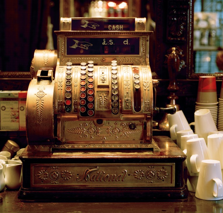 Vintage brass National cash register with ornate decorative details and numbered buttons.