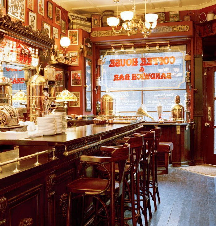 Interior of The Bridge coffee bar in London with red walls, brass fixtures, framed artwork and vintage coffee-house decor.