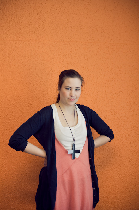Helene Auramo, head of Zipipop, poses against an orange background wearing a pink top and navy cardigan.