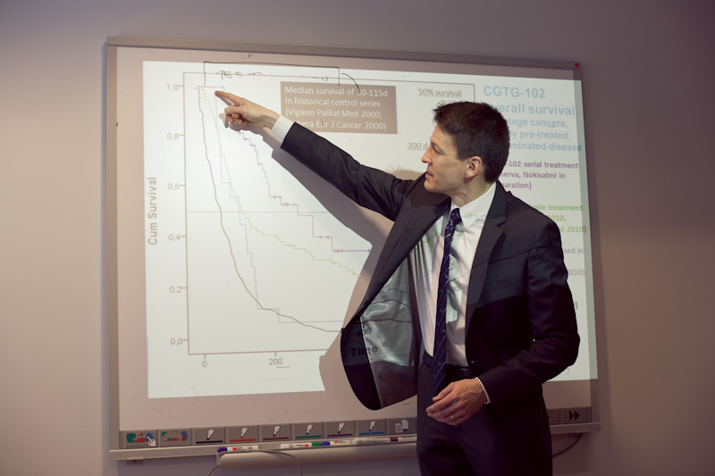Pekka Simula, Oncos CEO, pointing to cancer survival charts on a presentation screen.