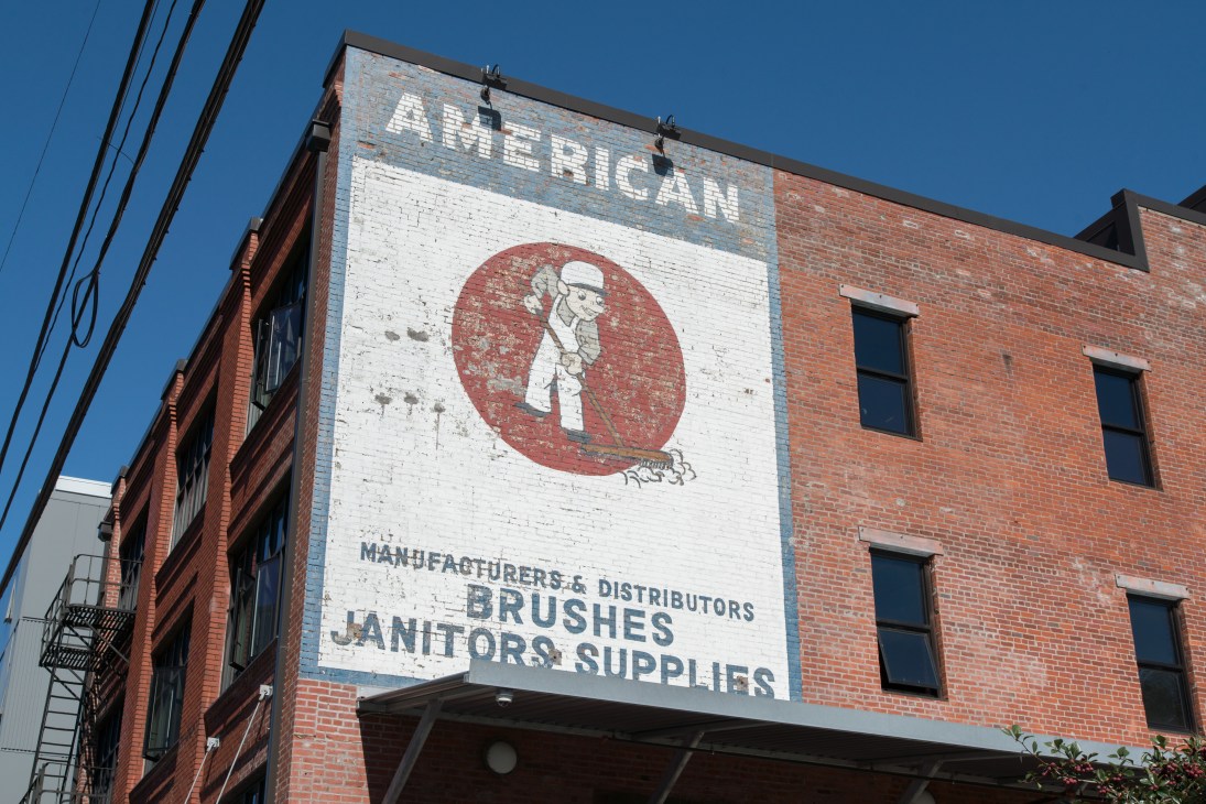 Weathered brick building with vintage American brush company advertisement painted on exterior wall