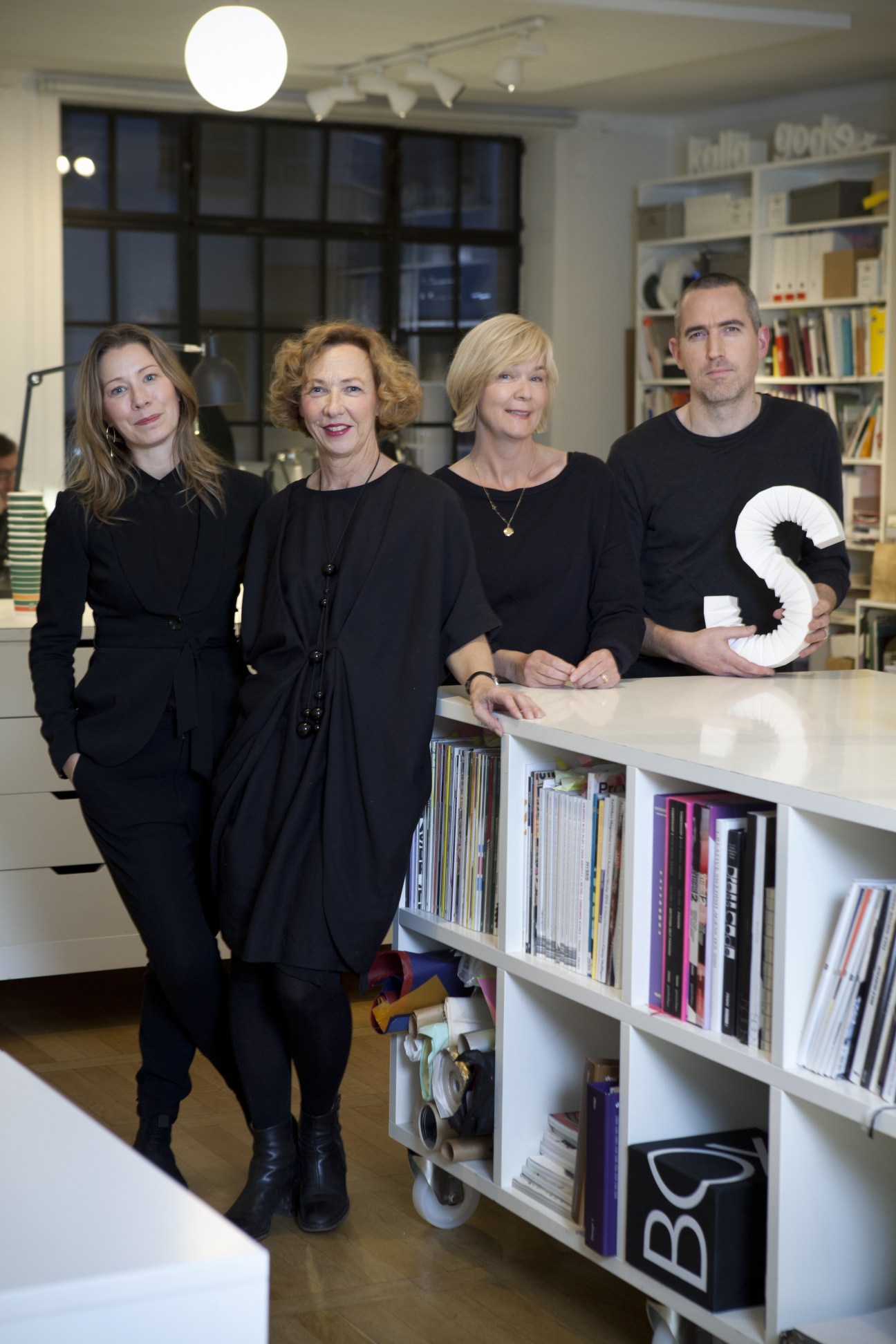Four BVD partners posing in their Stockholm studio office with bookshelves and design materials.